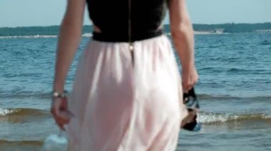 sarhoş kadın suya bir partiden sonra bir kadeh şarap ile sahilde yürüyor