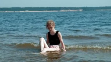 sarhoş kadın suya bir partiden sonra bir kadeh şarap ile sahilde yürüyor