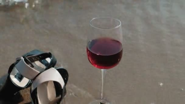 Shoes lie on the seashore, a glass of wine lies beside — Stock Video