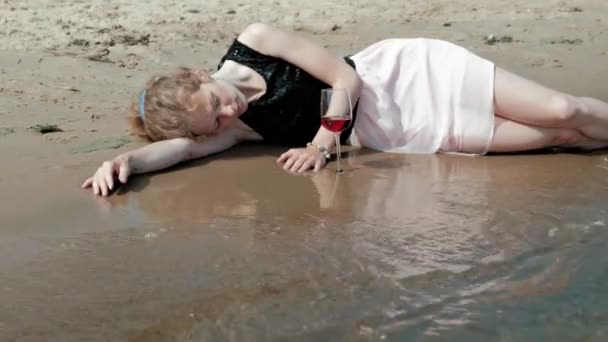 Μεθυσμένος γυναίκα που βρίσκεται στην παραλία με ένα ποτήρι κρασί μετά από ένα κόμμα — Αρχείο Βίντεο