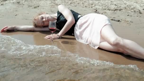 Berusad kvinna ligger på stranden med ett glas vin efter en fest — Stockvideo