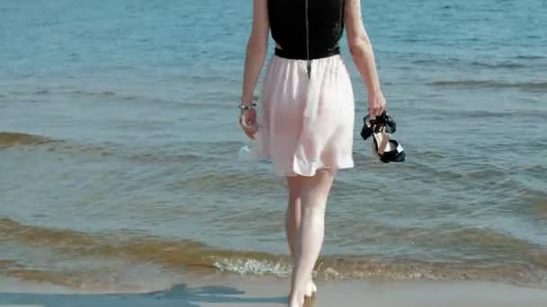 Пьяная женщина входит в воду на пляже с бокалом вина после вечеринки — стоковое видео