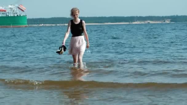 Berusad kvinna promenader i vattnet på stranden med ett glas vin efter en fest — Stockvideo