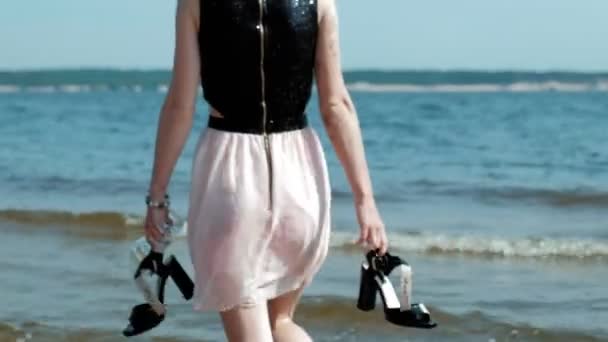 Berusad kvinna promenader i vattnet på stranden med ett glas vin efter en fest — Stockvideo