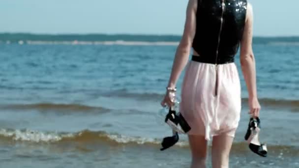 Opilá žena chodí do vody na pláži se sklenkou vína po večírku — Stock video
