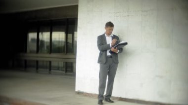 Kentin iş adamı. Bir takım elbise ve evrak çantası giyiyor. O belgeler üzerinden baktı ve smartphone üzerinde görüşmeler