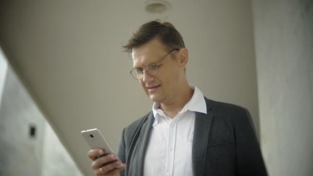 Affärsman i staden. Han bär en kostym och portfölj. Han ser genom dokument och samtal på din smartphone — Stockvideo