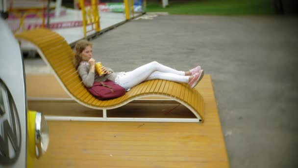 Young woman with milkshake and laptop outdoors on a comfortable creative bench — Stock Video