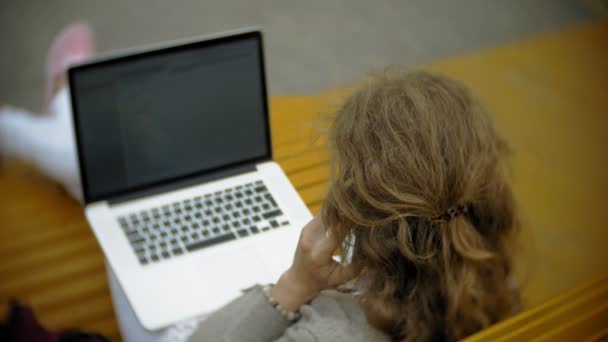 Jonge vrouw met milkshake en laptop buiten op een comfortabele creatieve Bank — Stockvideo