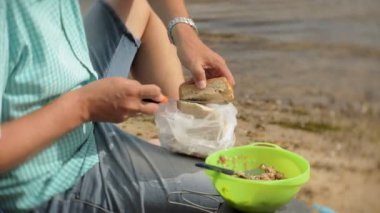 Bir adam bir kazana arka planda bir çadır ile bir kamp çevresinde yiyor.