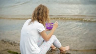 Bir kadın bir kazana arka planda bir çadır ile bir kamp çevresinde yiyor.