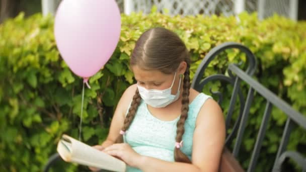 Jolie fille dans un respirateur lisant un livre dans le parc sur un banc — Video