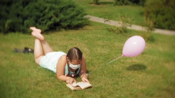 可爱的女孩在呼吸器读一本书在公园4K — 图库视频影像