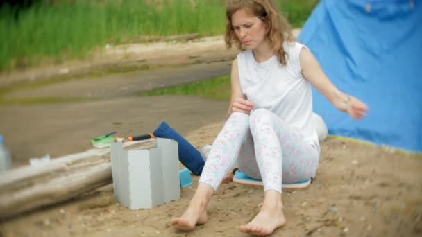 Las mujeres cocinando alimentos en un tazón de fuente en el camping con tienda de campaña en el fondo . — Vídeos de Stock