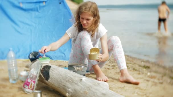 Las mujeres cocinando alimentos en un tazón de fuente en el camping con tienda de campaña en el fondo . — Vídeo de stock