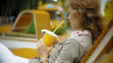 Milkshake ve cep telefonu açık havada rahat bir yaratıcı banka olan kadın