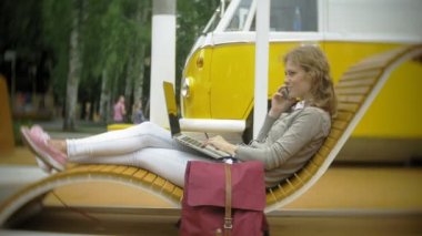 Milkshake ve dizüstü bilgisayar açık havada rahat bir yaratıcı banka olan kadın