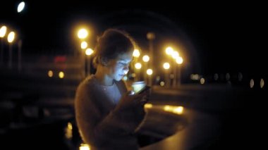 Şehir merkezinde ise cep telefonuna gece genç kadın mesaj. Mutlu kadın manifatura ile şehir içinde smartphone.