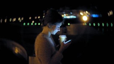 Şehir merkezinde ise cep telefonuna gece genç kadın mesaj. Mutlu kadın manifatura ile şehir içinde smartphone.