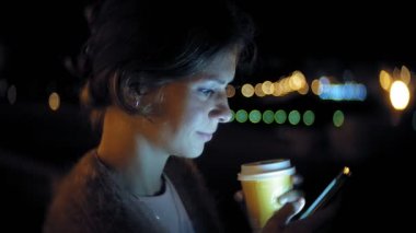 Şehir merkezinde ise cep telefonuna gece genç kadın mesaj. Mutlu kadın manifatura ile şehir içinde smartphone.