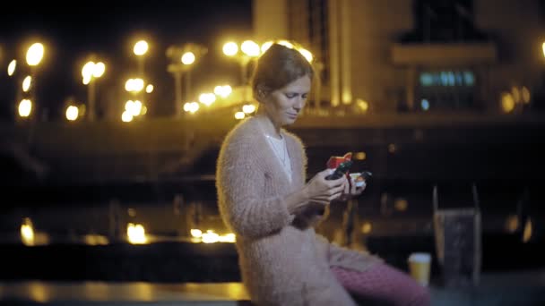 Young woman eating french fries in the night outdoors by the light of lanterns — Stock Video