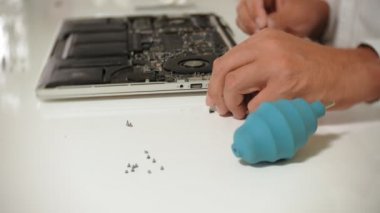 Bir adam dizüstü bilgisayarı tamir ediyor. Bilgisayar tamiri kavramı. Dizüstü bilgisayarı tornavidayla tamir et. Ana kartın donanımının bakımı. Disk tutucu, bilgisayar onarımı