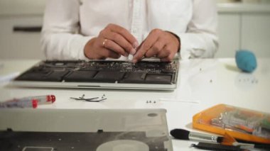 Bir adam dizüstü bilgisayarı tamir ediyor. Bilgisayar tamiri kavramı. Dizüstü bilgisayarı tornavidayla tamir et. Ana kartın donanımının bakımı. Disk tutucu, bilgisayar onarımı
