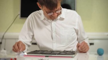 Bir adam dizüstü bilgisayarı tamir ediyor. Bilgisayar tamiri kavramı. Dizüstü bilgisayarı tornavidayla tamir et. Ana kartın donanımının bakımı. Disk tutucu, bilgisayar onarımı