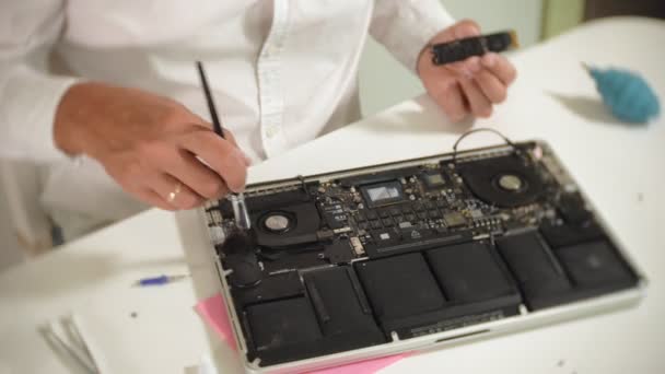 Um homem está a reparar um portátil. O conceito de reparação de computadores. Fechar-se de homem reparar placa-mãe laptop com uma chave de fenda. Manutenção do hardware da placa-mãe. Suporte de disco, reparação de computadores — Vídeo de Stock