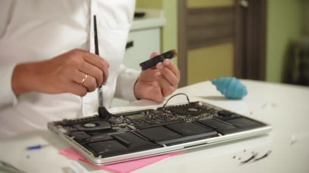 Un hombre está reparando un portátil. El concepto de reparación de computadoras. Primer plano de hombre reparación placa base portátil con un destornillador. Mantenimiento del hardware de la placa base. Soporte de disco, reparación de computadoras — Vídeo de stock