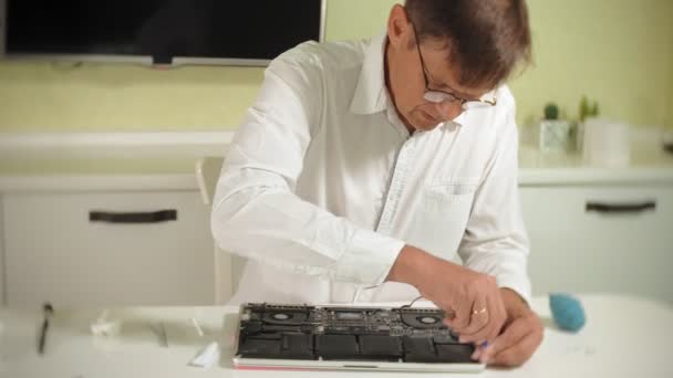 Un homme répare un ordinateur portable. Le concept de réparation d'ordinateurs. Gros plan de l'homme réparation ordinateur portable carte mère avec un tournevis. Entretien du matériel de la carte mère. Support de disque, réparation d'ordinateur — Video