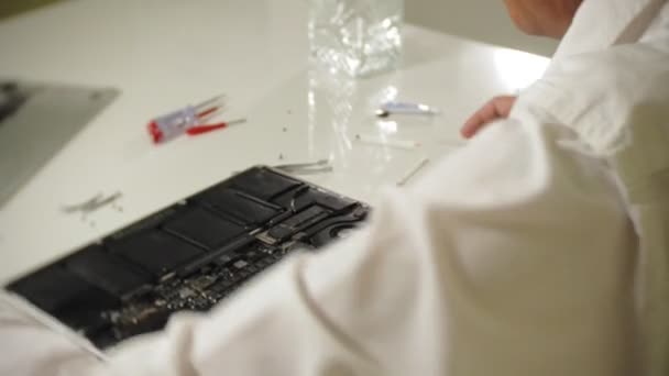 Un hombre está reparando un portátil. El concepto de reparación de computadoras. Primer plano de hombre reparación placa base portátil con un destornillador. Mantenimiento del hardware de la placa base. Soporte de disco, reparación de computadoras — Vídeos de Stock