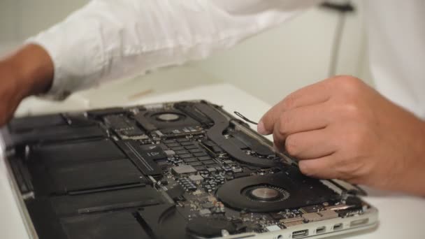 男がノートパソコンを修理している。コンピュータの修理の概念。ドライバで人の修理ノートパソコンのマザーボードを閉じます。マザーボードのハードウェアのメンテナンス。ディスクホルダー、コンピュータの修理 — ストック動画