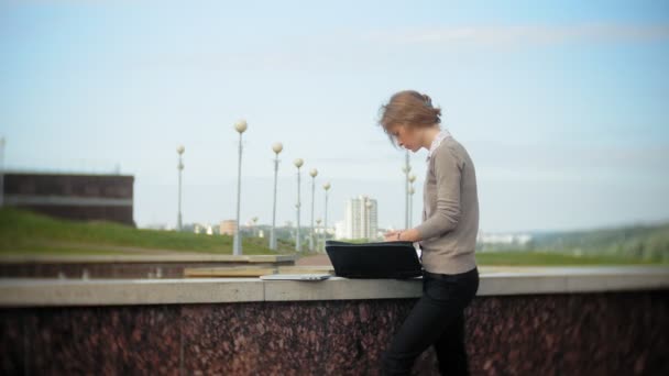 Giovane donna d'affari seduta sui gradini con un computer portatile nel business center, leggere documenti . — Video Stock