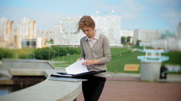 Jeune femme d'affaires assise sur les marches avec un ordinateur portable dans le centre d'affaires, lire des documents . — Video