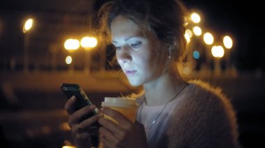 Şehir merkezinde ise cep telefonuna gece genç kadın mesaj. Mutlu kadın manifatura ile şehir içinde smartphone.