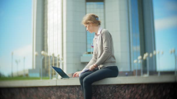 Ung affärskvinna sitter på trappan med en laptop i businesscentret, läsa dokument. — Stockvideo