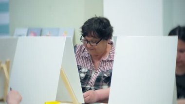 Sanat Okulu, yaratıcılık ve insanlar kavramı - grup öğrenci Sephalar, boya fırçaları ve stüdyoda, natürmort resim paletleri ile yaşlı ve genç insanlar çizmek