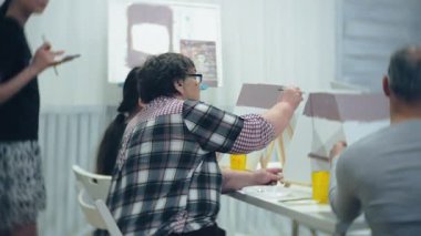 Sanat Okulu, yaratıcılık ve insanlar kavramı - grup öğrenci Sephalar, boya fırçaları ve stüdyoda, natürmort resim paletleri ile yaşlı ve genç insanlar çizmek