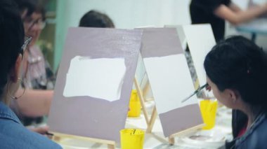 Sanat Okulu, yaratıcılık ve insanlar kavramı - grup öğrenci Sephalar, boya fırçaları ve stüdyoda, natürmort resim paletleri ile yaşlı ve genç insanlar çizmek