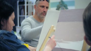 Sanat Okulu, yaratıcılık ve insanlar kavramı - grup öğrenci Sephalar, boya fırçaları ve stüdyoda, natürmort resim paletleri ile yaşlı ve genç insanlar çizmek