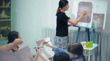 Sanat Okulu, yaratıcılık ve insanlar kavramı - grup öğrenci Sephalar, boya fırçaları ve stüdyoda, natürmort resim paletleri ile yaşlı ve genç insanlar çizmek