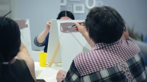 Scuola d'arte, creatività e concetto di persone - gruppo di studenti con cavalletti, pennelli e tavolozze che dipingono nature morte in studio, vecchi e giovani disegnano — Video Stock