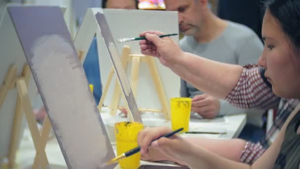 École d'art, concept de créativité et de personnes - groupe d'étudiants avec des chevalets, pinceaux et palettes peinture nature morte à l'atelier, les personnes âgées et les jeunes dessinent — Video