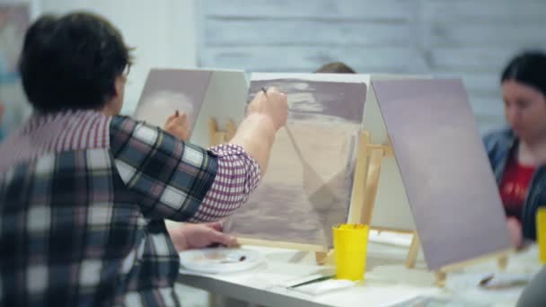 Konstskola, kreativitet och människor koncept - grupp studenter med staffli, penslar och paletter målning stilleben på studio, gamla och unga människor Rita — Stockvideo