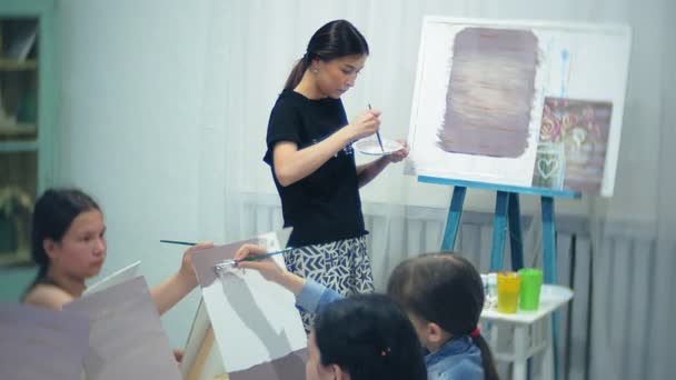 Konstskola, kreativitet och människor koncept - grupp studenter med staffli, penslar och paletter målning stilleben på studio, gamla och unga människor Rita — Stockvideo