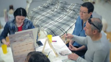 Sanat Okulu, yaratıcılık ve insanlar kavramı - grup öğrenci Sephalar, boya fırçaları ve stüdyoda, natürmort resim paletleri ile yaşlı ve genç insanlar çizmek