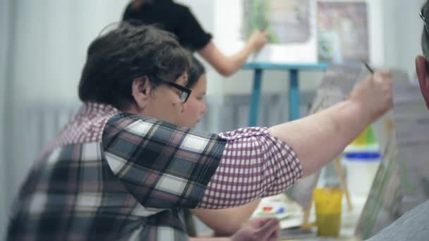 Escuela de arte, creatividad y concepto de personas - grupo de estudiantes con caballetes, pinceles y paletas pintando bodegones en el estudio, viejos y jóvenes dibujan — Vídeo de stock