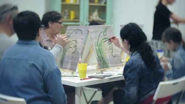 Art school, creativity and people concept - group of students with easels, paintbrushes and palettes painting still life at studio, old and young people draw — Stock Video