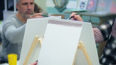 Sanat Okulu, yaratıcılık ve insanlar kavramı - grup öğrenci Sephalar, boya fırçaları ve stüdyoda, natürmort resim paletleri ile yaşlı ve genç insanlar çizmek